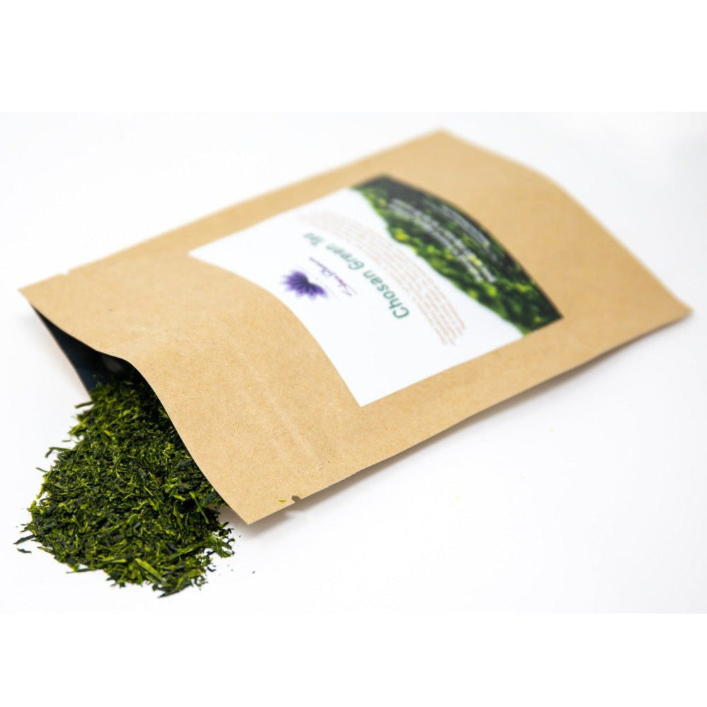This image shows a bag of Shen Blossom's Chosen Green Tea being poured out onto a white counter