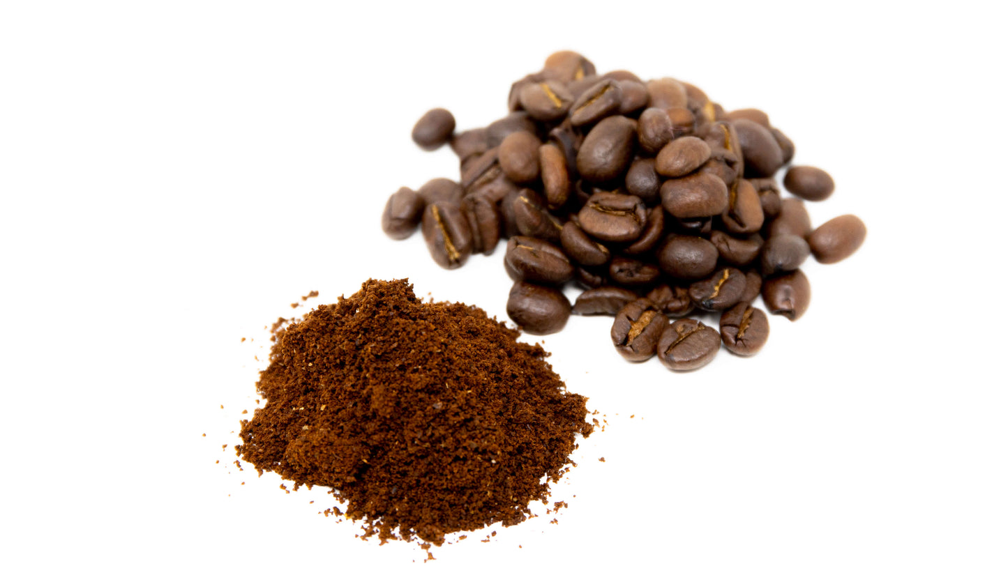 A pile of ground coffee and coffee beans photographed on a white background