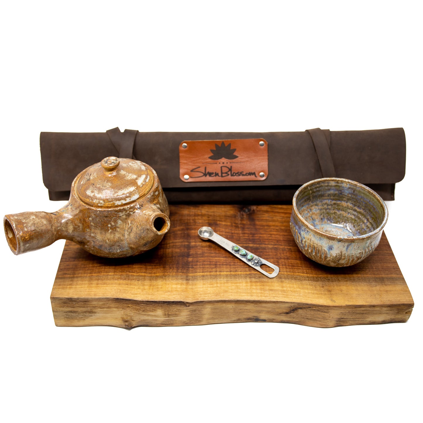 A Shen Blossom knife case, ceramic tea pot & cup and silver 1/4 tsp spoon sits on a wooden serving tray