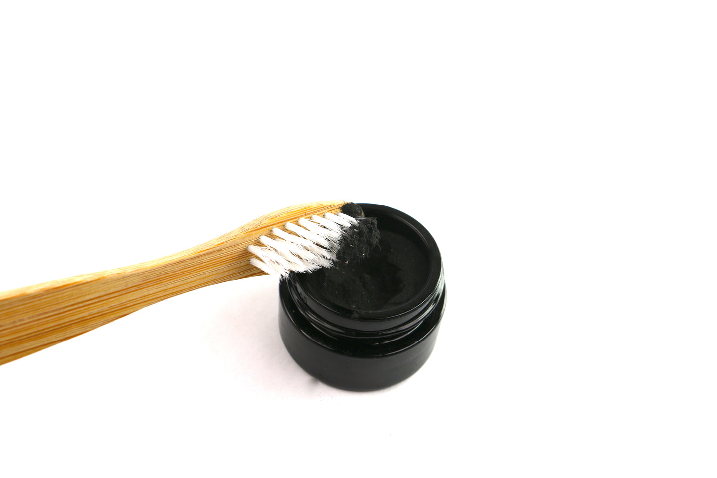 Pictured is a tooth brush being dipped into Shen Blossom's Tooth Polish for use.