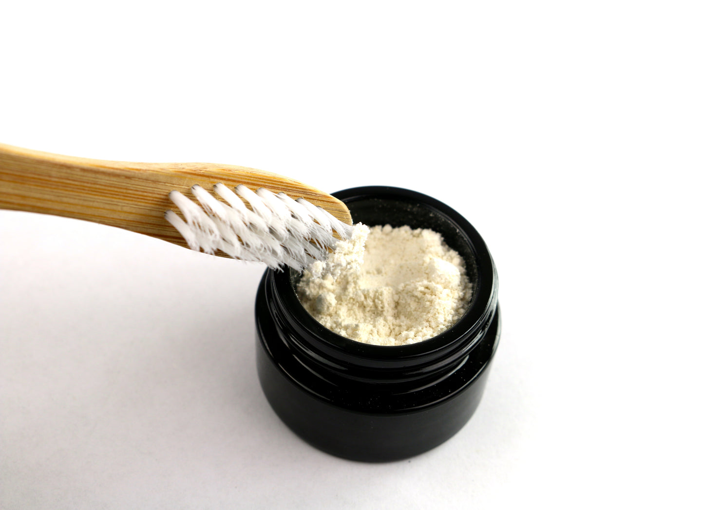 An up close picture of a tooth brush being dipped into Shen Blossom's Tooth Cleanser.