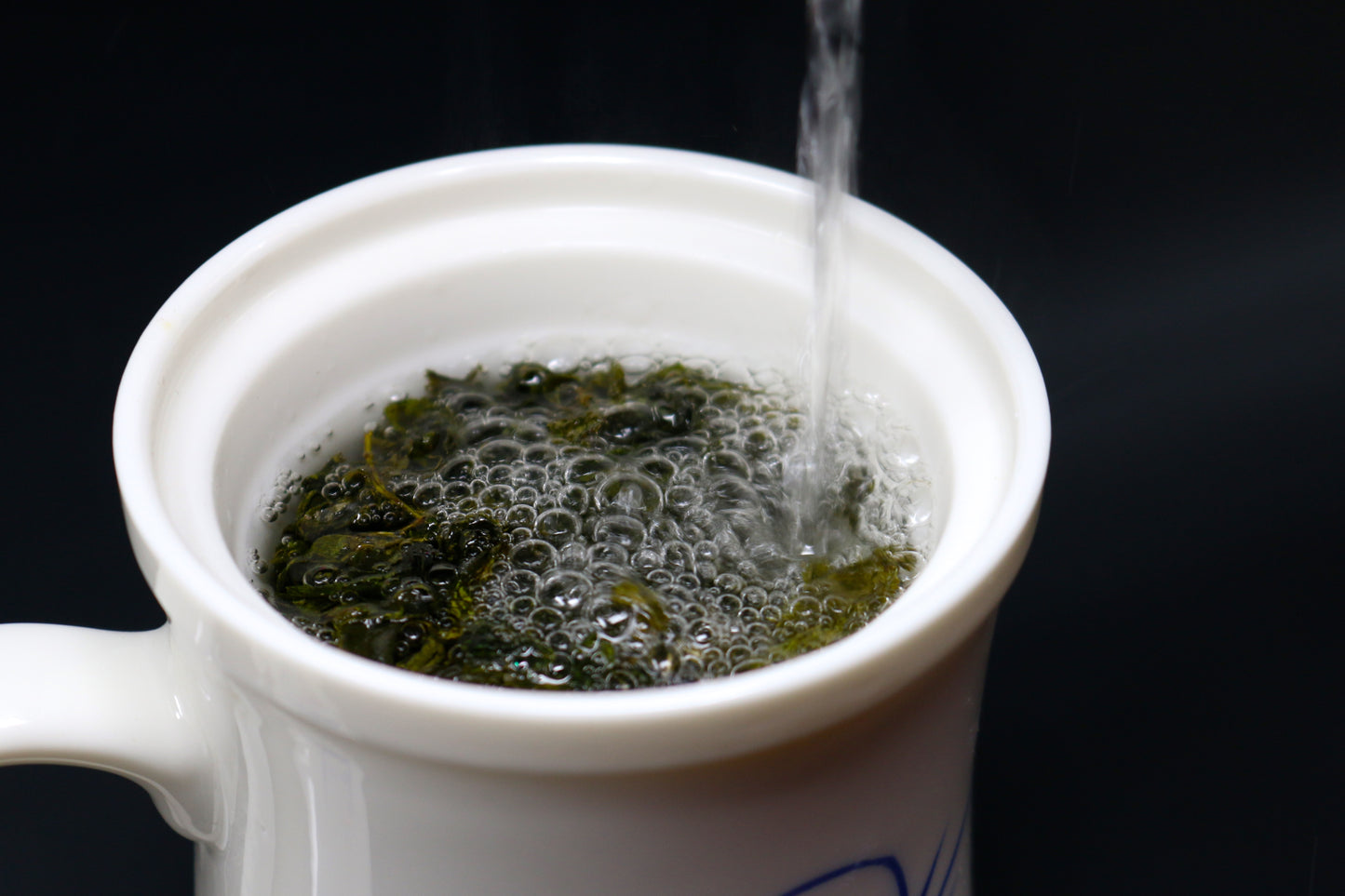 This photo shows water being poured over a serving of Shen Blossom's Amacha Loose Leaf Tea