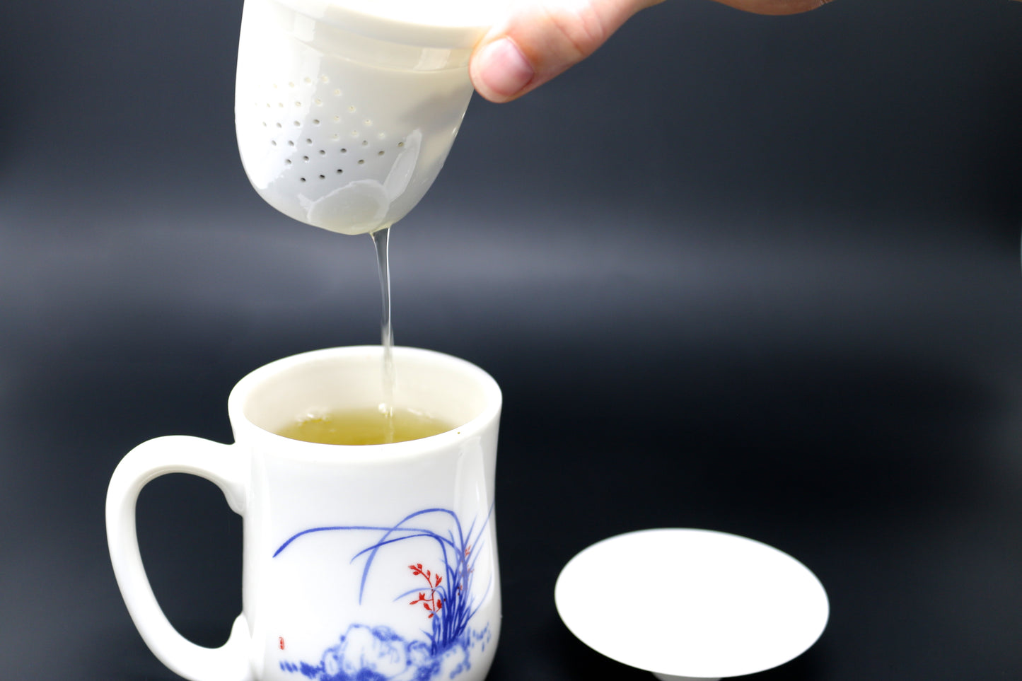 Pictured is someone removing the infuser from their tea cup of Shen Blossom's Amacha Loose Leaf Tea