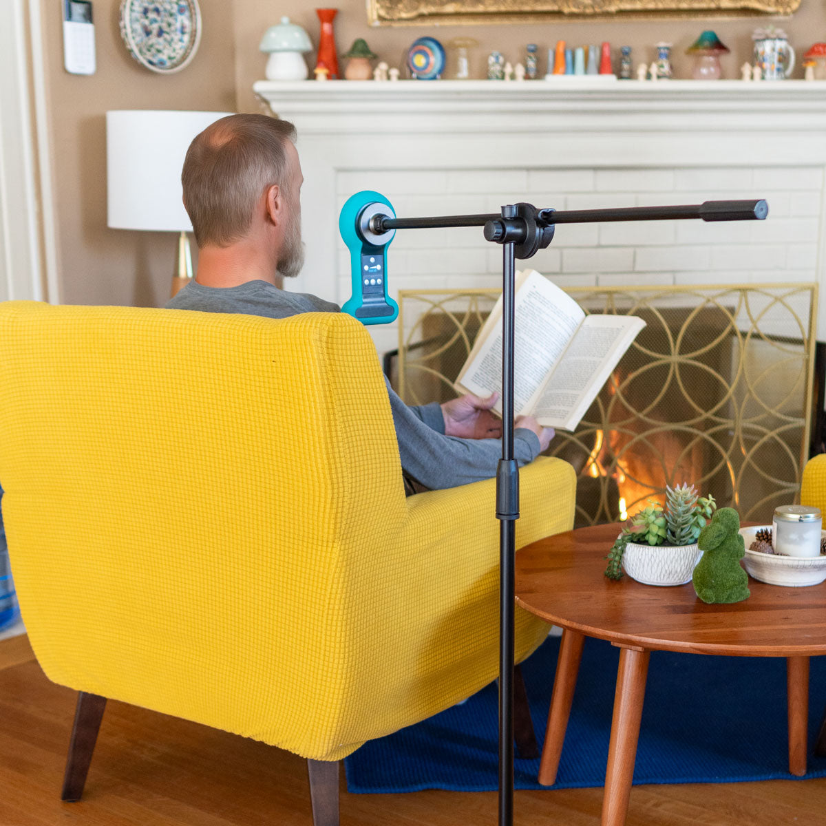 
                  
                    A person reads a book while using their Chi Palm that's connected to the positioning stand in the comfort of their home
                  
                