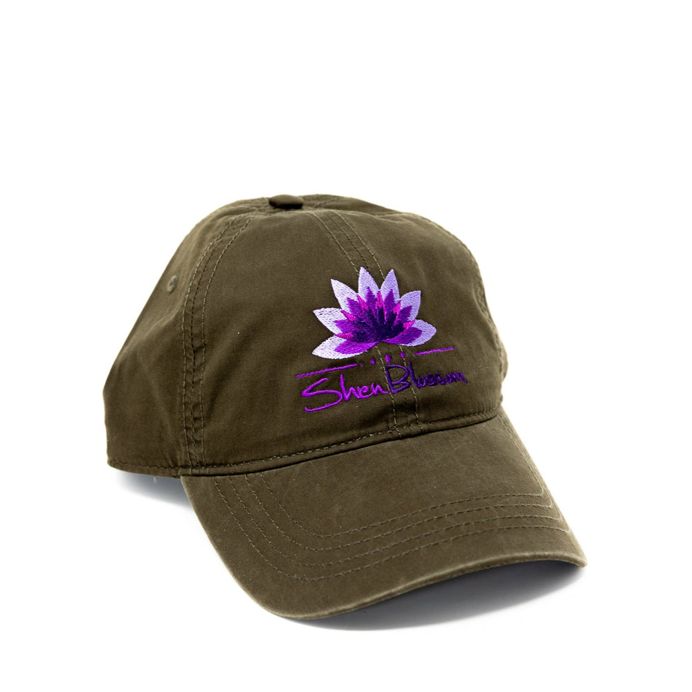 A forrest green hat with purple Shen Blossom lotus logo pictured on a white background 